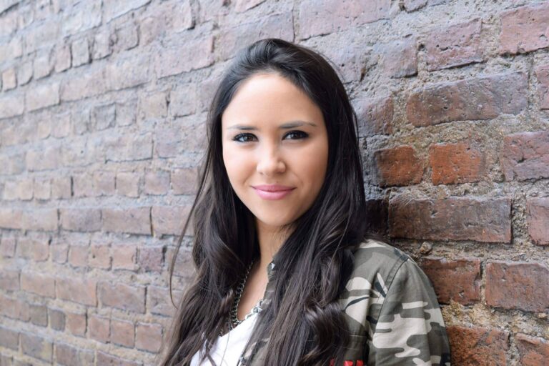 Portrait of young hispanic woman posing against a brick wall.