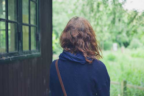 Woman sitting by a window looking outside thoughtfully