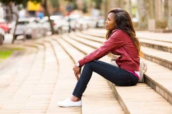 Woman sitting on stairs with head down in distress