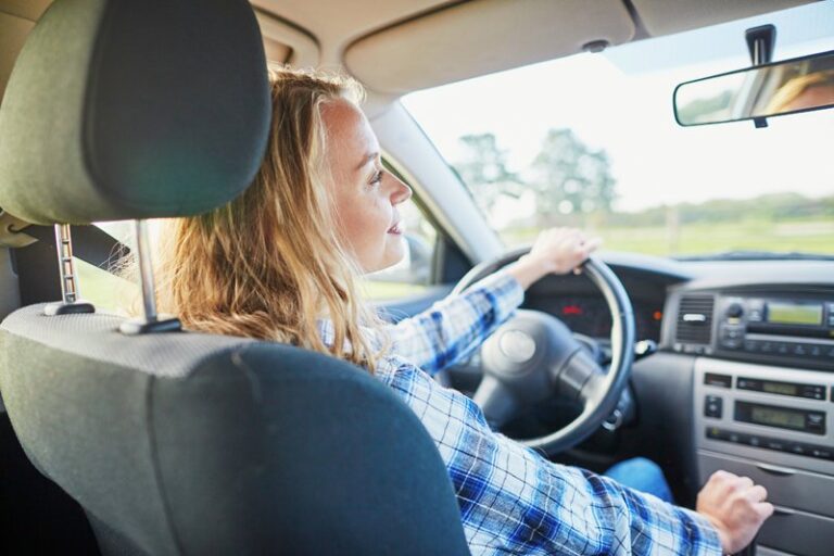Woman driving a car with a focused and serious expression.