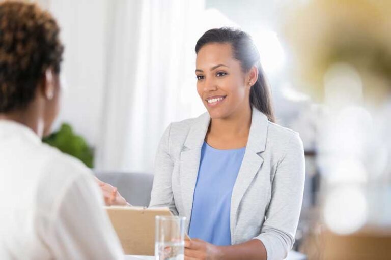 Female nurse smiling while speaking with a patient in an office setting about RealOptions low to no-cost pap smears tests.