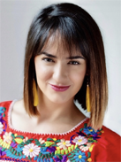 RealOptions Education Staff. A headshot of a smiling woman with dark, bob-length hair and bangs, wearing a bright red top with colorful floral embroidery and long yellow earrings.