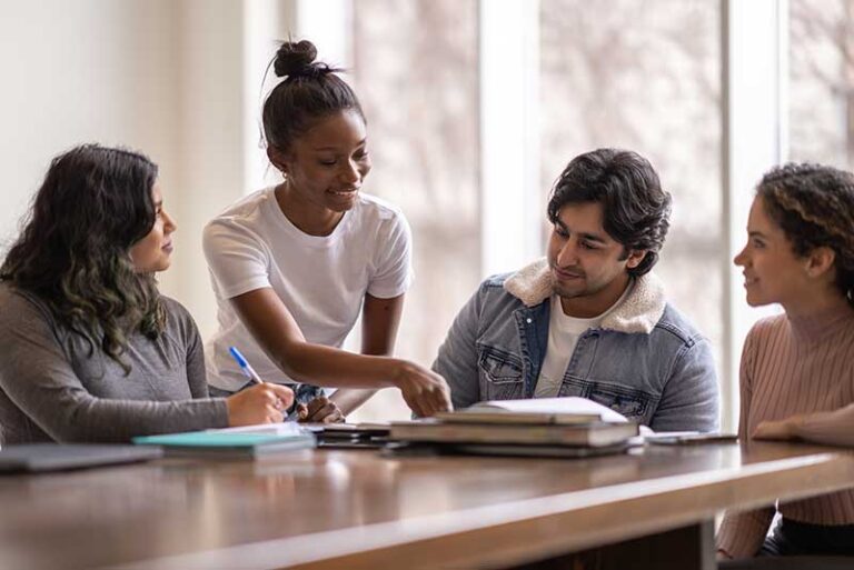 Group of young adults sitting around a table having a supportive discussion.